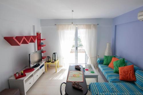 a living room with a blue couch and a tv at Laconic bay view suite in Mavrovoúnion