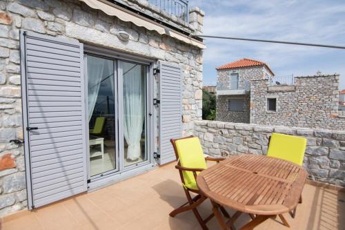 a patio with a wooden table and two yellow chairs at Laconic bay view suite in Mavrovoúnion