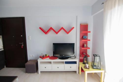 a living room with a television on a white cabinet at Laconic bay view suite in Mavrovoúnion