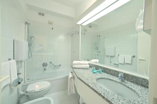 a bathroom with a tub and a toilet and a sink at Hotel Europa & Concordia in Alassio