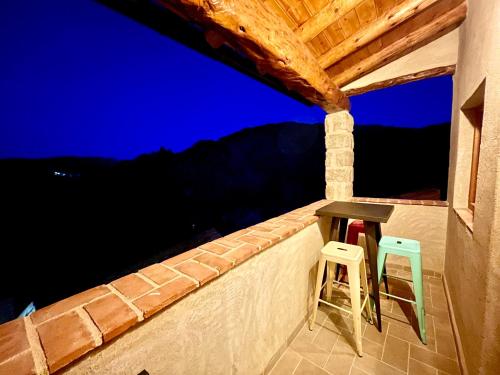 a table and two stools on a balcony at night at El Kubo in Olba