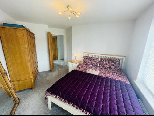 um quarto com uma cama roxa e um armário de madeira em Whiteclouds em Cheshunt