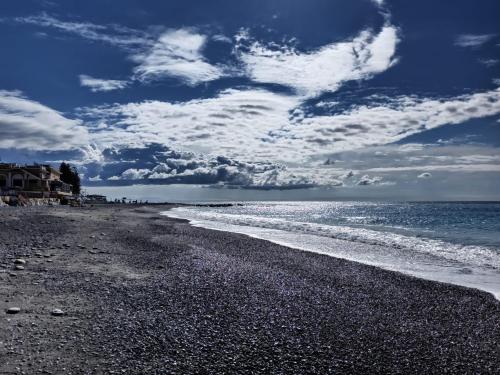 a beach with a cloudy sky and the ocean at HOST HOUSE in Bordighera