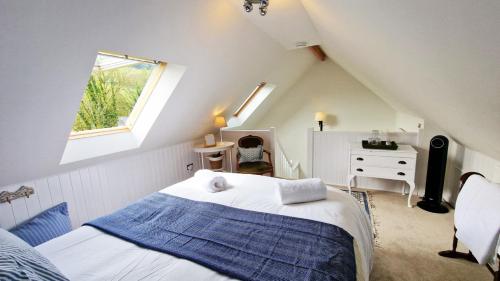 - une chambre mansardée avec un lit et une fenêtre dans l'établissement Keep Cottage - East Devon, à Southleigh