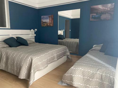 een blauwe slaapkamer met 2 bedden en een spiegel bij Room 10 in Taranto