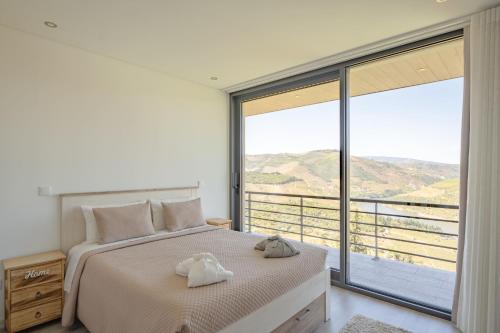 a bedroom with a bed and a large window at Feel Discovery Alvim's Douro in Folgosa