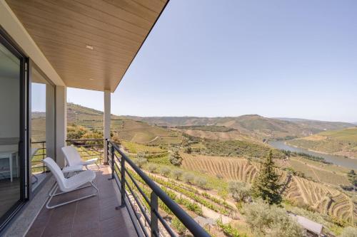 a balcony with two chairs and a view of a river at Feel Discovery Alvim's Douro in Folgosa