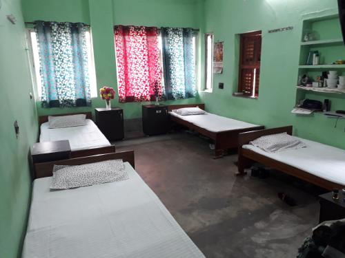 kolkataにあるPushpak Guest House Boys, Near DumDum metro Stationのベッド3台と窓2つが備わる客室です。