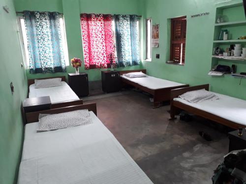 a room with three beds and two windows at Pushpak Guest House Boys, Near DumDum metro Station in kolkata