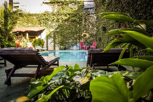 a pool with chairs and plants in a yard at Hospedagem La Bilbaina in Porto Seguro
