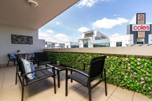 a balcony with chairs and tables and a hedge at Charming Apt 1min to Marketplace Gungahlin - Hosted by CanStay in Harrison