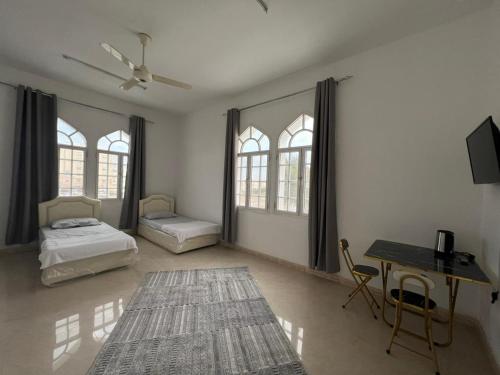 een kamer met 2 bedden, een bureau en een tafel bij Hostel Alborz in Muscat