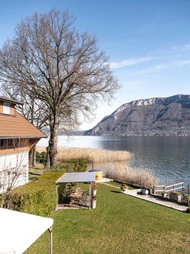 - une vue sur un lac avec un arbre et une maison dans l'établissement Venez Chez Vous Villa Aux Premières Loges, à Sévrier