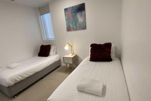 a bedroom with two beds and a table with a lamp at 2BR Light Filled and Cosy Apartment - Hosted by CanStay in Phillip