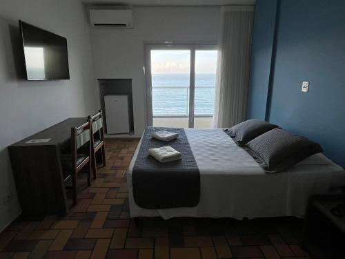 a bedroom with a bed with a view of the ocean at Hotel Quatro Estações in Guarapari