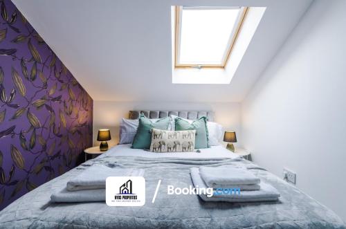 Un dormitorio con una cama con almohadas azules y una ventana en 4 Bedroom House Free Parking By NYOS PROPERTIES Short Lets & Serviced Accommodation Manchester, en Mánchester