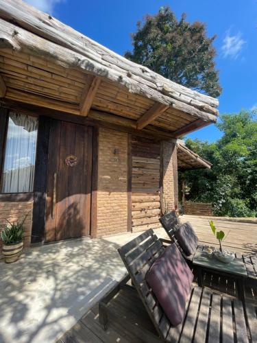 een houten patio met een bank op een terras bij Cabanas Arcádia in Engenheiro Paulo de Frontin