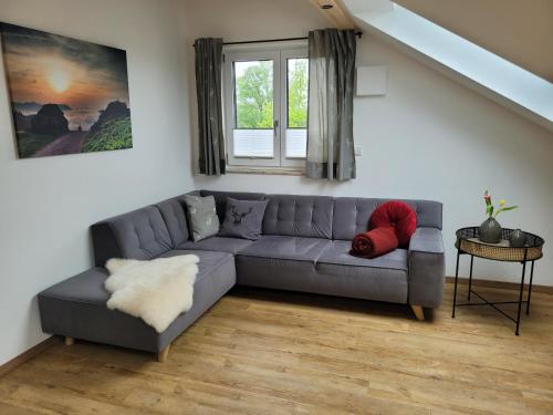 a living room with a gray couch and a window at Ferienwohnung Klauserhof in Grassau