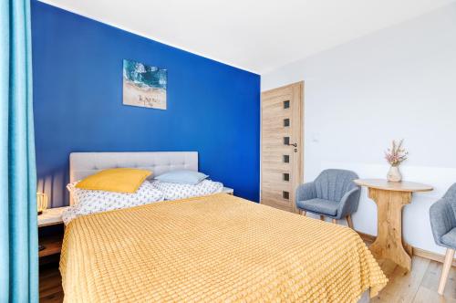 a blue bedroom with a bed and a table and chairs at KEJB Chałupy in Chałupy