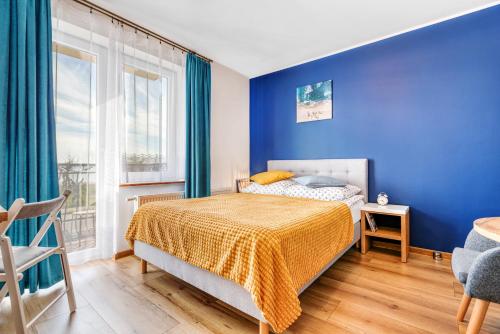 a blue bedroom with a bed and a window at KEJB Chałupy in Chałupy