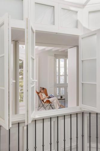 a woman sitting in a chair on the balcony of a house at Candelaria10 in Cádiz