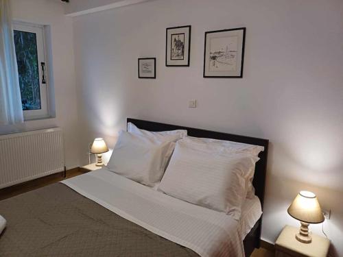 - une chambre avec un lit avec des draps blancs et 2 lampes dans l'établissement Anatoli apartment, à Mytilène