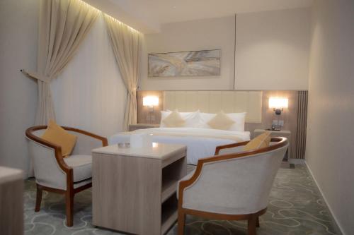 ein Hotelzimmer mit einem Bett und zwei Stühlen in der Unterkunft فندق نارس بلس النزهة - Nars Plus Hotel in Dschidda