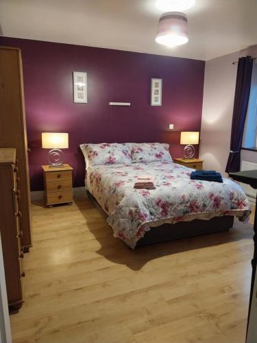 ein Schlafzimmer mit einem Bett und einer lila Wand in der Unterkunft Pegs Cottage in Limerick