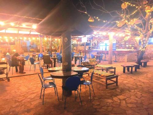 a restaurant with tables and chairs at night at Blue Palm Resort Ghana in Abia