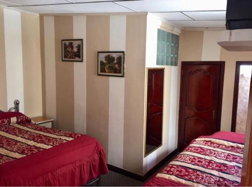 een kamer met 2 bedden en een spiegel aan de muur bij Hotel Metropolitano in Loja
