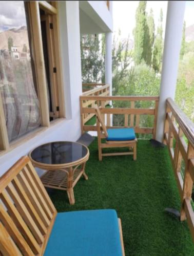 a porch with two chairs and a table on the grass at Ewam Chunka in Leh