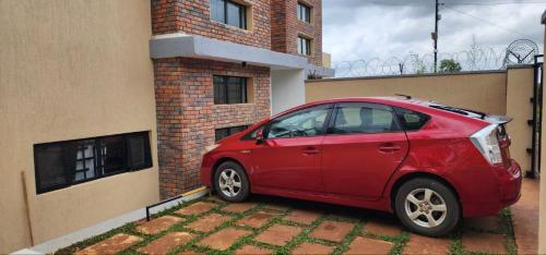 een rode auto geparkeerd voor een gebouw bij Scenic Kigali-View Townhouse in Kigali