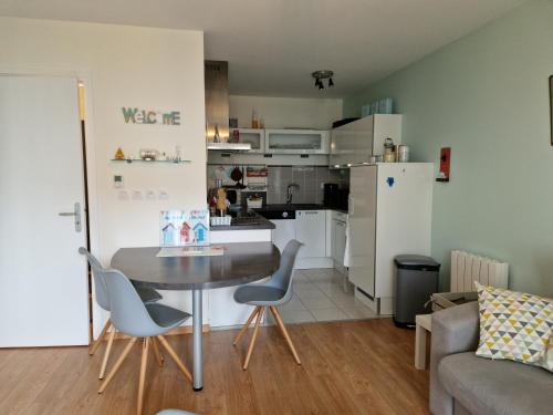 un salon avec une table et des chaises et une cuisine dans l'établissement Le Bellem, à Courseulles-sur-Mer