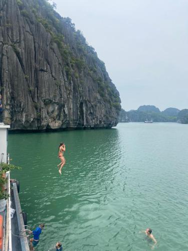 a woman jumping into a body of water at Tran Chau Garden Home in Cat Ba