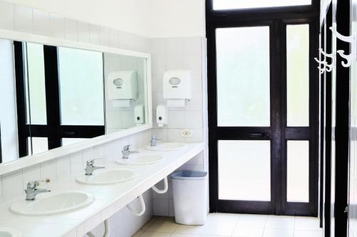 a bathroom with three sinks and a large mirror at Camping Village la Chiocciola in Capannole