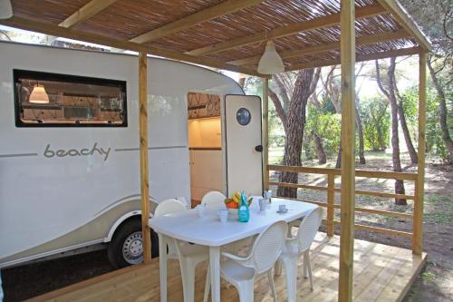 uma mesa e cadeiras em frente a uma caravana em Riva di Ugento Beach Camping Resort em Ugento