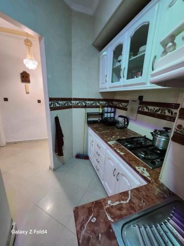 a kitchen with white cabinets and a stove top oven at complexe printemps n 155 et 3 in Tangier