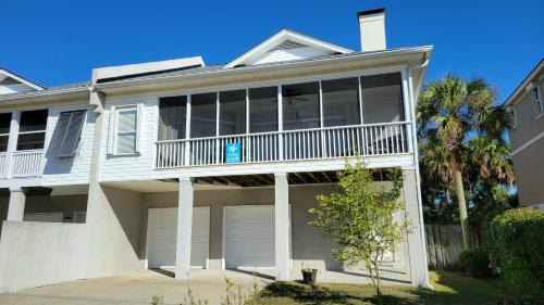 a large white house with a balcony and palm trees at 6-B 13th Street by Tybee Vacation Rentals in Tybee Island