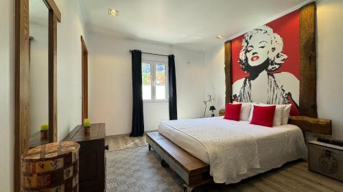 a bedroom with a bed with a painting on the wall at The Modern & Recycled House in Machico