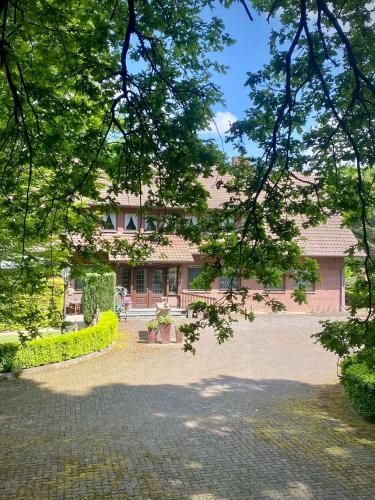 ein Haus mit einer gepflasterten Auffahrt davor in der Unterkunft Jagdhaus zu Amtern Apartment Rose in Holdorf