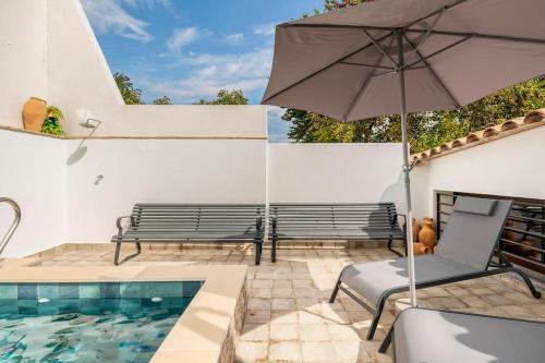 un patio con bancos y una sombrilla junto a una piscina en Casa Sierraverde Fuenteheridos by MSHOLIDAYS, en Fuenteheridos