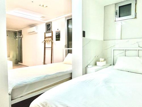 a bedroom with two beds and a tv on the wall at Look Home Guesthouse in Seoul