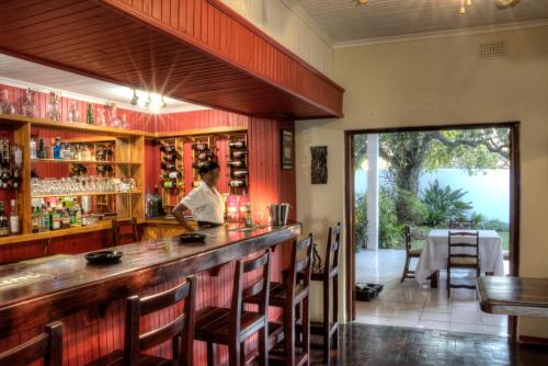 a bar in a restaurant with a person standing at the counter at The Musketeers Lodge in Bulawayo