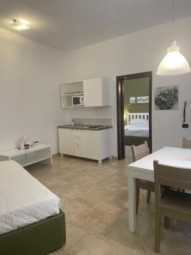 a bedroom with a bed and a table and a kitchen at San Domenico Residence by BADIA NUOVA in Trapani