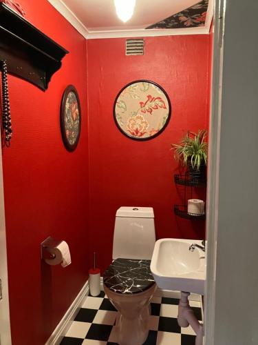 La salle de bains rouge est pourvue de toilettes et d'un lavabo. dans l'établissement Magderuds gårdshus, à Beateberg