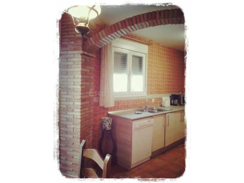una cocina con una pared de ladrillo y un arco en Casa Rural Zaragoza, en Almonacid de la Sierra