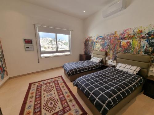 sypialnia z 2 łóżkami, oknem i dywanem w obiekcie Downtown Living Boutique Apartments w mieście Amman