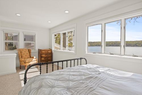 1 dormitorio con paredes y ventanas blancas y 1 cama en Luxury Conesus Lakeside Dock Modern Amenities en Livonia
