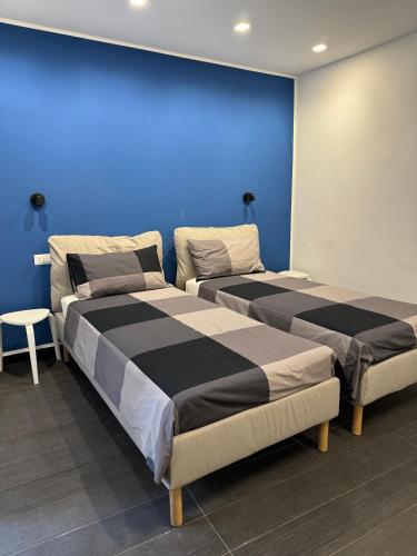 two beds in a room with a blue wall at Black Room & Breakfast in Bari