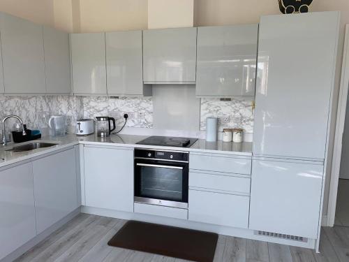 cocina blanca con armarios blancos y fogones en Entire Penthouse 30 mins to city center via luas, en Dublín